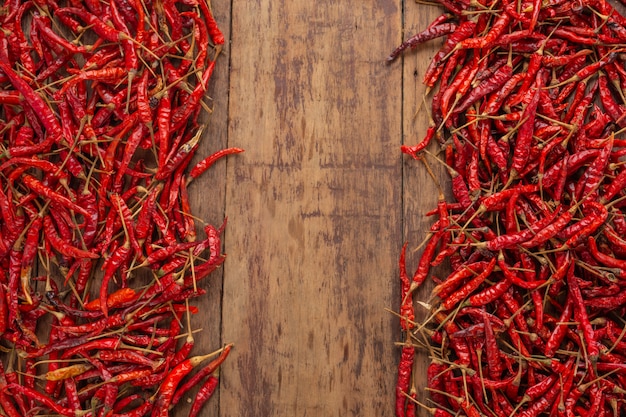 Red dried chilies that are stacked on the plank.