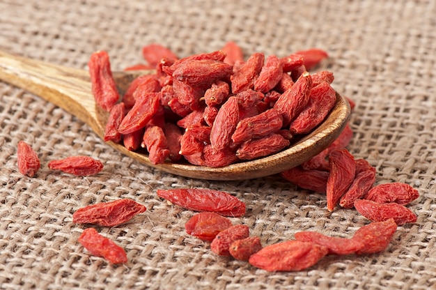 Red dried goji berries in wooden spoon