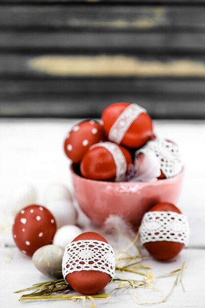 Red Easter eggs on wood knotted lace tape, close-up, still life