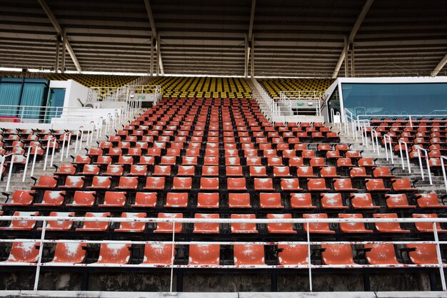 Красный Пустые и старые пластиковые сиденья на стадионе.