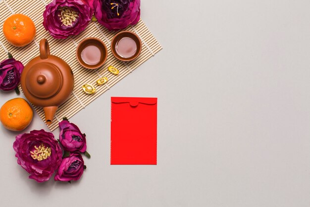 Бесплатное фото Красный конверт рядом с чайным сервизом