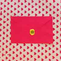 Free photo red envelope on table with hearts pattern