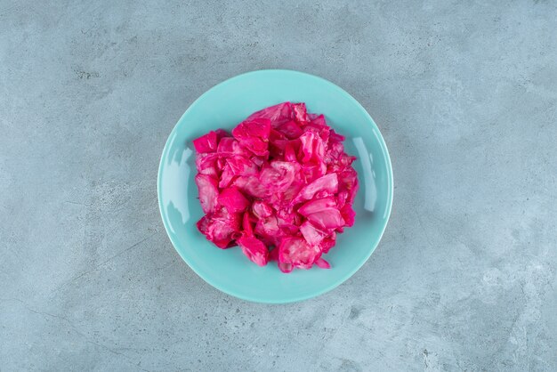 Red fermented sauerkraut on plate , on the blue table. 