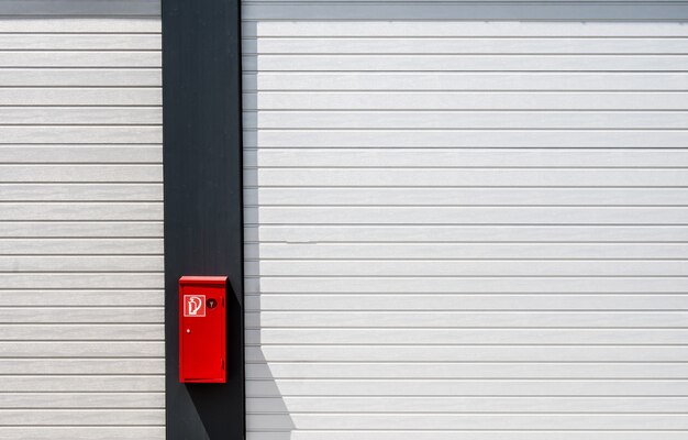 Red fire box hung on a black and white surface with lines