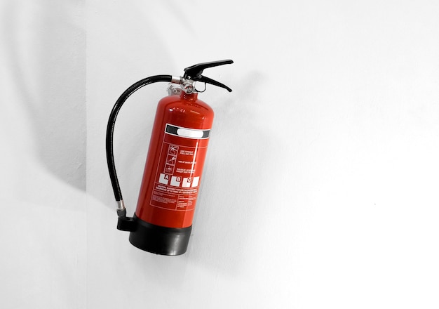 Free photo red fire extinguisher on a white wall