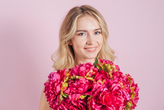 Red flower roses bouquet in front of smiling young woman against pink backdrop