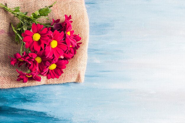 Free photo red flowers bouquet on canvas on table