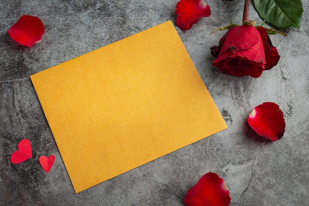 Red flowers of rose and envelop on dark background