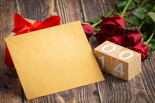 Red flowers of rose and envelop on on dark wood background