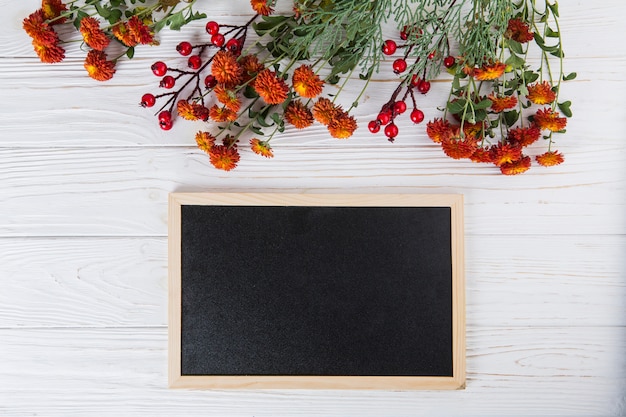 Red flowers with blank chalkboard on white table