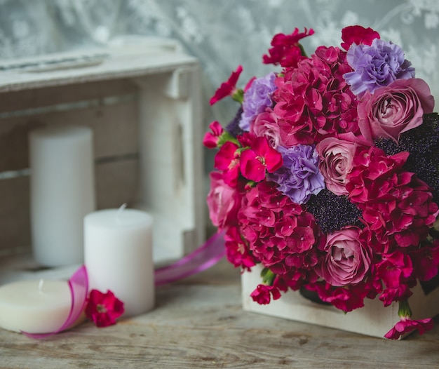 Red fower bouquet standing ona book and candles around on a table