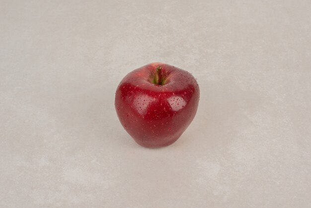 A red, fresh apple on white table.