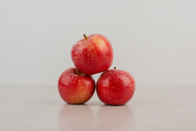 Red, fresh apples on white table.