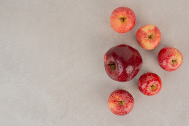 Red, fresh apples on white table.