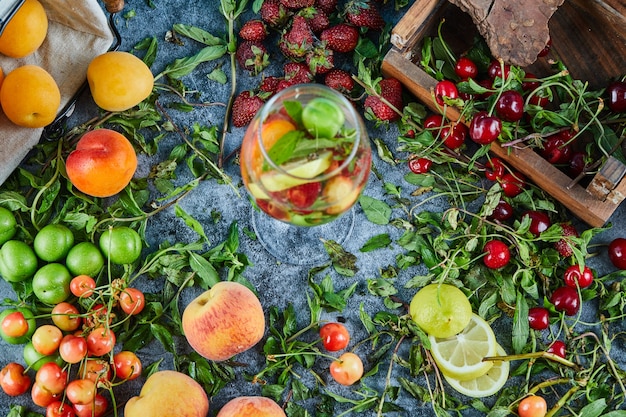 Ciliege fresche rosse sulla scatola di legno con un bicchiere di succo di frutta e frutta fresca