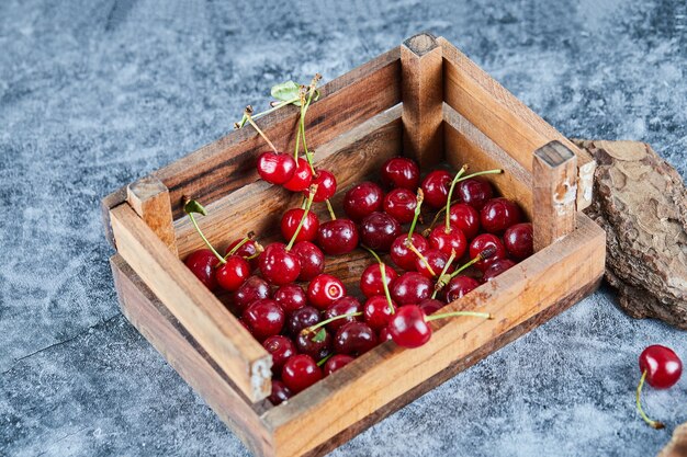Red fresh juicy cherries in a wooden box with leaves