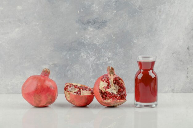 Red fresh pomegranates and fresh juice on white table.