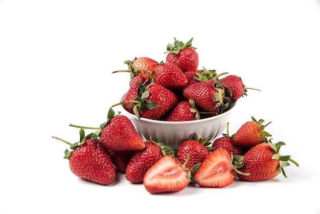 Red fresh strawberries with green leaves in white saucer