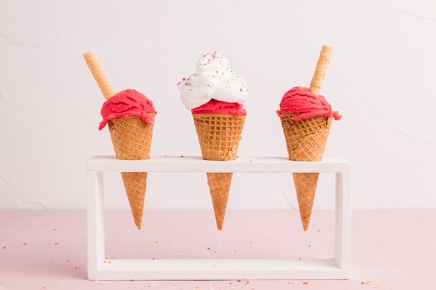 Красный замороженный шарик мороженого в конусах с вафельной соломкой