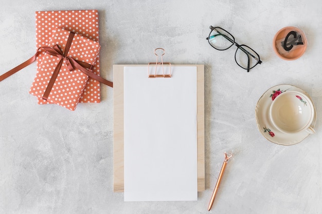 Red gift boxes, eyeglasses, clipboard and cup on dish