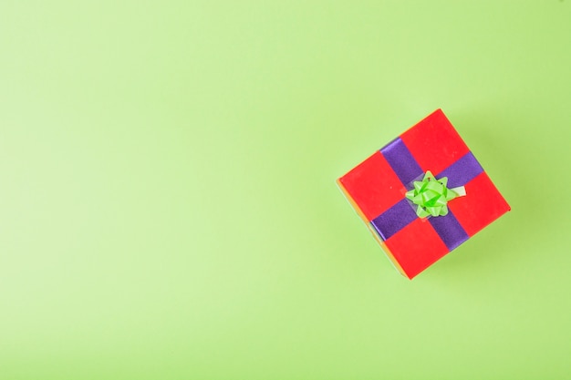 Red gift wrapped with blue and green ribbon over the green background