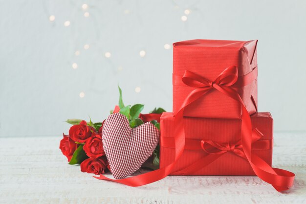 Red gifts with a bouquet of roses beside