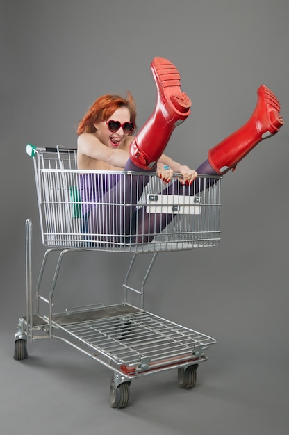 Красная девушка едет по магазинной тележке