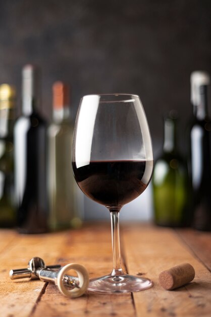 Красный бокал вина с бутылками позади