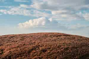 Free photo red granite stone against a blue sky with clouds selective focus wallpaper idea