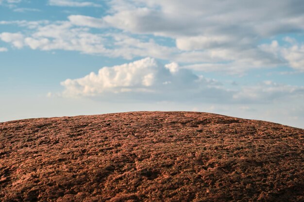 Red granite stone against a blue sky with clouds selective focus wallpaper idea