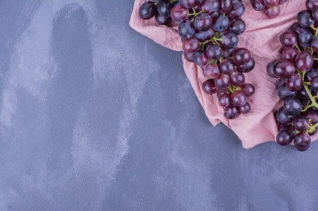 Грозди красного винограда на куске розового полотенца.