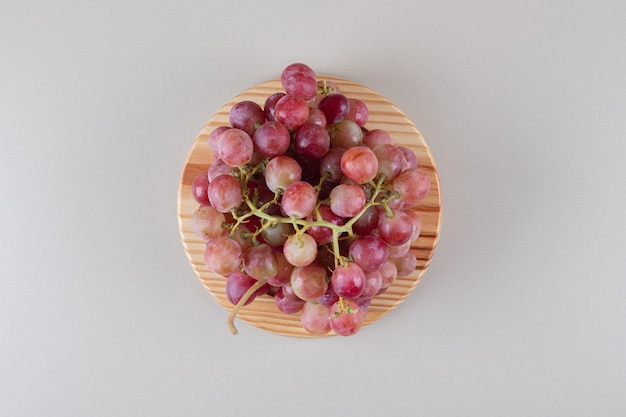 Грозди красного винограда на деревянном блюде на мраморе