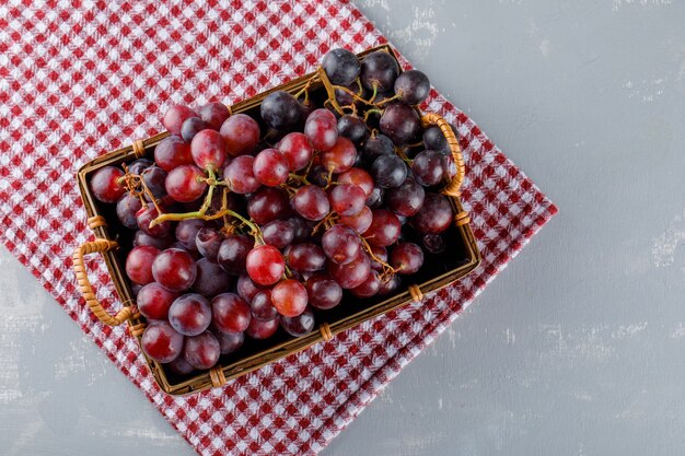 Red grapes in a basket flat lay on picnic cloth and plaster