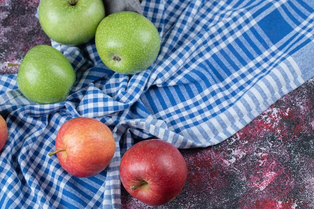 Red and green apples isolated on blue checked towel.