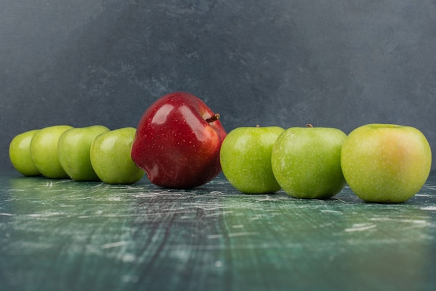 Red and green apples on marble table.