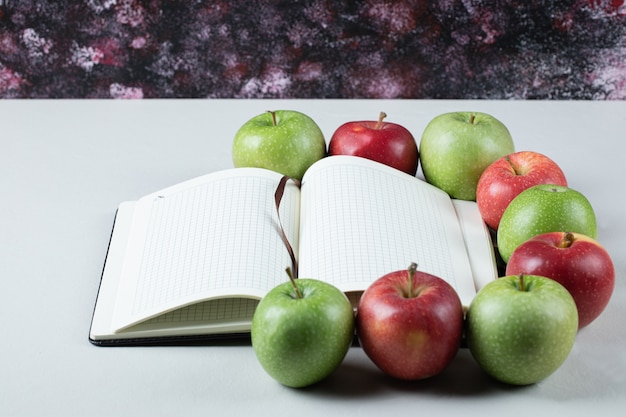 Free photo red and green apples with a blank recipe book around