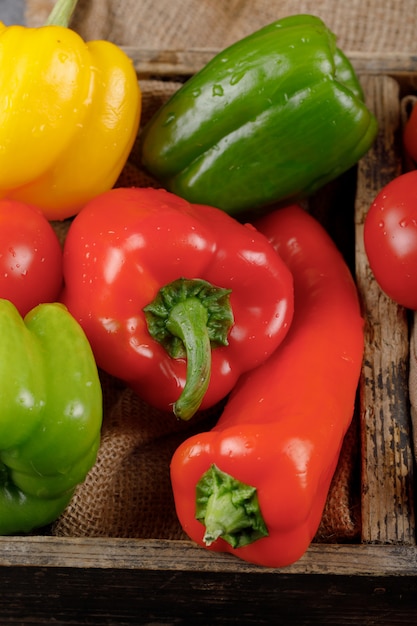 Red and green bell peppers in a rustic tray. Top view.