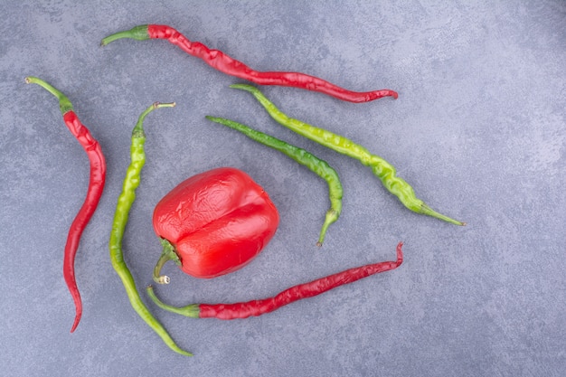 Free photo red and green chili peppers on grey background.