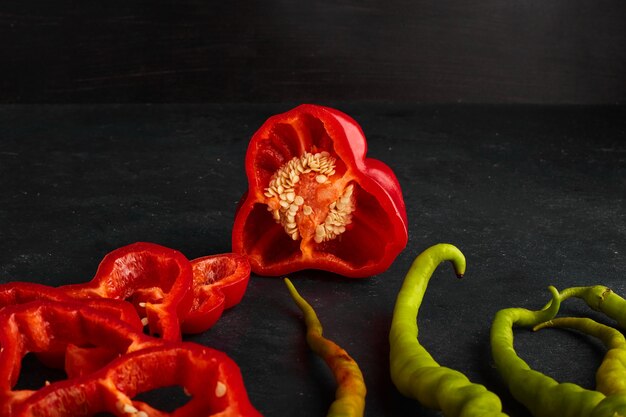 Red and green chili peppers sliced and served on black board. 