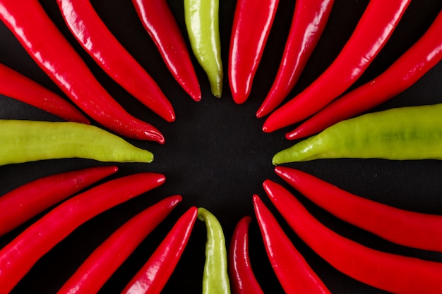 red and green chili peppers top view on black surface