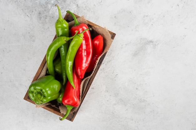 Red and green chili peppers in a wooden tray.