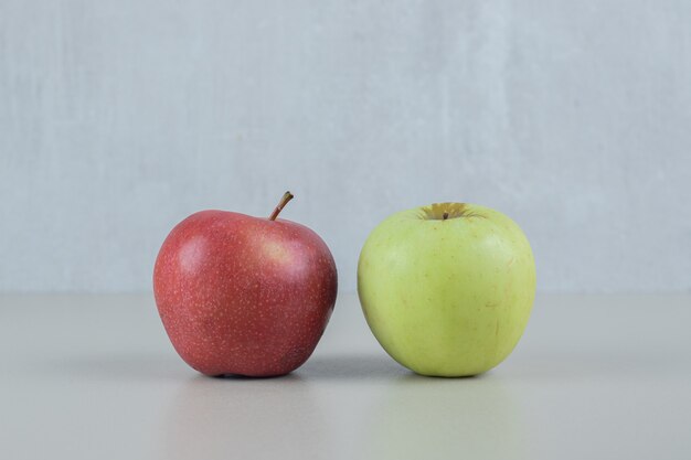 灰色の壁に赤と緑の新鮮なリンゴ。