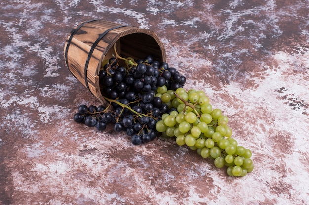 Red and green grape bunches out of a wooden bucket
