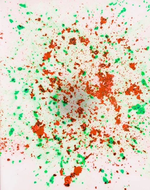 Red and green holi color powder on white surface backdrop