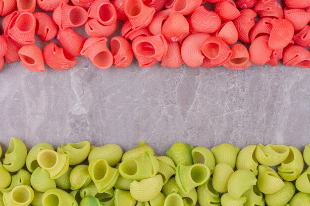 Red and green uncooked pastas on the marble surface