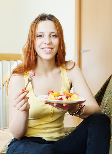 red-hair girl eating fruits salad