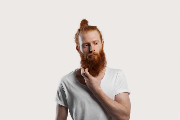 Red-haired attractive man try to remember new idea and scratch red beard and look away with skeptical expression