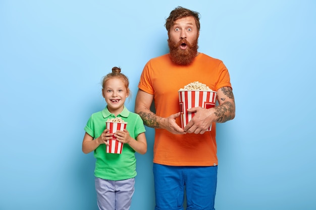 Red haired daughter and father eat popcorn