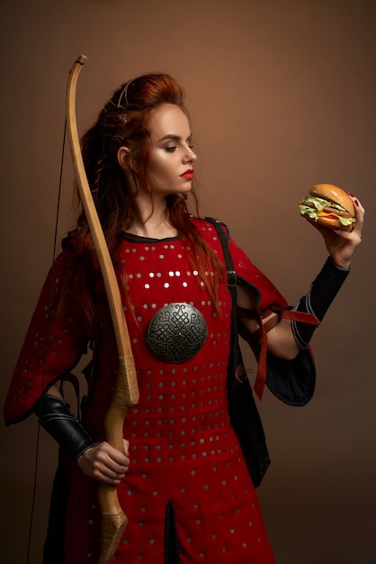 Red haired female warrior with bow keeping hamburger