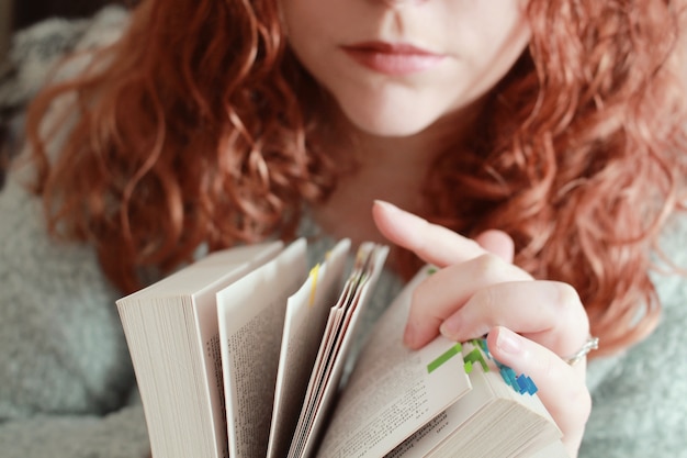 Red-haired female with a serious facial expression looking through a book